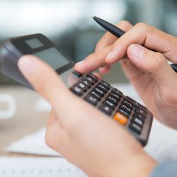 Close-up of male hands using calculator. Unrecognizable accountant holding pen when pushing button on calculator. Finance concept